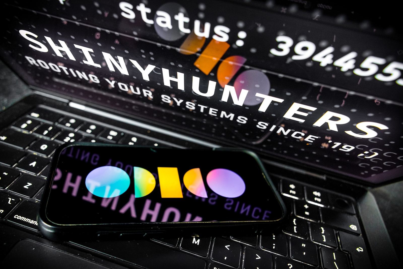 Smartphone met het Odido-logo op een toetsenbord, met tekst van hackersgroep ShinyHunters op de achtergrond
